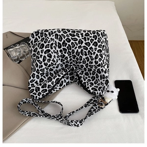 Detail view of leopard print crossbody bag with plush charm and adjustable strap