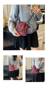 Détail du sac seau rouge à motif léopard avec cordon de serrage et logo blanc imprimé