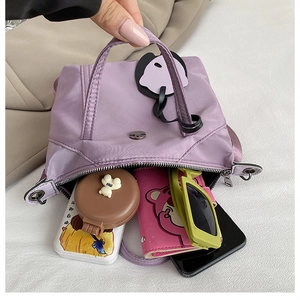 Intérieur spacieux du sac bandoulière en nylon violet montrant le rangement du mobile