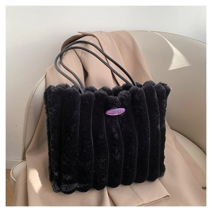 Détail d'un cabas noir en fausse fourrure à rayures verticales et logo sur fauteuil beige