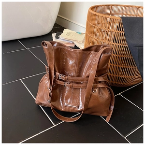 Dettaglio della borsa a secchiello marrone lucido con fibbie decorative in pelle fine