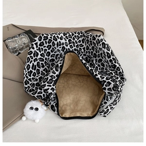 Detail view of large leopard print canvas tote bag with black zipper and plush monster charm