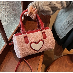 Detailed view of pink faux shearling texture with red leather heart embroidery on bag
