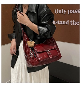 Burgundy hobo shoulder bag with plush bear charm styled on a model in a leather jacket