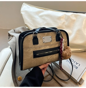 Detail showing beige canvas tote with black trim and a cute brown plush bear charm