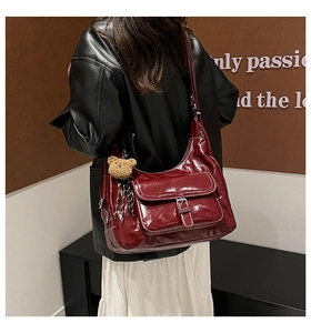 Macro shot of burgundy glossy tote bag with flap pocket and cute bear charm pendant