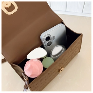 Internal view of brown textured bag showing phone and cosmetics for daily capacity