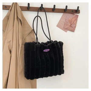 Gros plan d'un sac cabas en fausse fourrure noire texturée suspendu à un crochet
