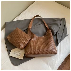 Dettaglio del set borsa hobo intrecciata marrone con pochette coordinata su tessuto