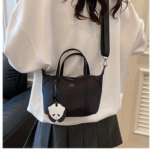 Détail du sac bandoulière en nylon noir avec un pendentif panda mignon