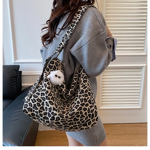 Macro shot of stylish leopard print canvas tote with a cute white plush ball keychain detail