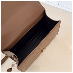 Detail view of brown embossed bag interior with gold magnetic snap and hardware