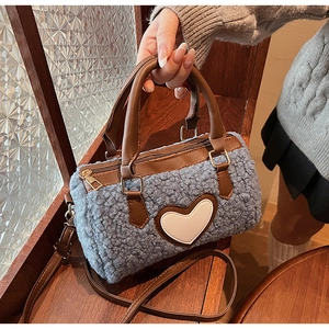 Macro view of blue plush pillow bag showing brown leather trim and heart patch