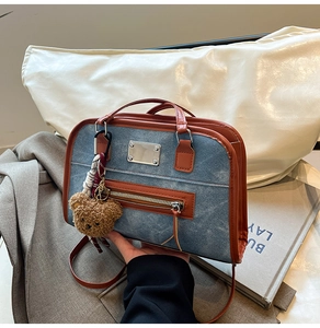 Detail of blue denim hobo bag with brown leather trim and cute teddy bear pendant charm
