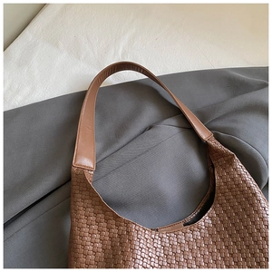 Dettaglio della borsa tote intrecciata marrone con ampia tracolla in pelle pregiata