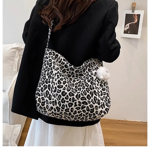 Macro shot of large leopard print canvas tote bag with a white fluffy pompom keychain detail