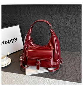 Detail of burgundy leather hobo bag with contrast stitching and front buckle pocket