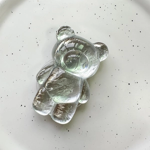 Macro detail of clear resin bear-shaped phone grip with a glossy crystal finish