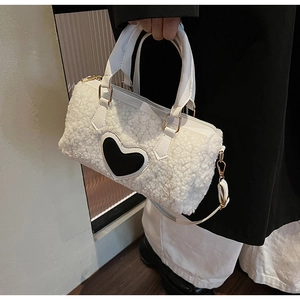 Detail of white faux fur pillow bag with black heart patch and golden hardware accents