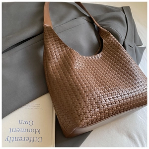 Dettaglio della trama borsa Hobo intrecciata marrone su blazer grigio stile minimale