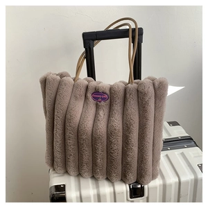 Sac fourre-tout gris en peluche avec écusson fashion girl sur une valise blanche