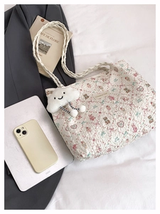 Detail of printed white tote bag with cute cartoon patterns and plush cloud pendant