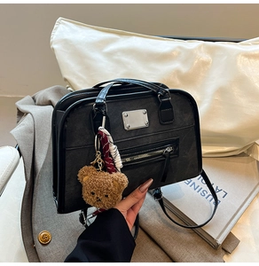 Detail of vintage black tote bag with silver hardware and a plush bear pendant charm