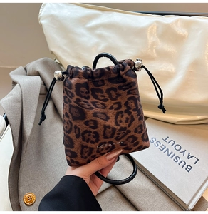 Detail of leopard print bucket bag with drawstring closure and black round handle