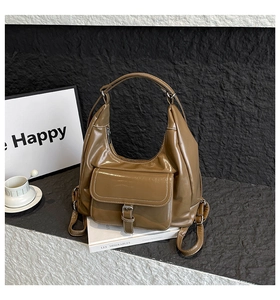 Close-up of shiny caramel brown PU leather Hobo bag featuring a front pocket and decorative buckle