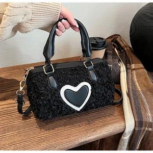 Close-up of fluffy black teddy shoulder bag with heart patch in a cozy cafe setting