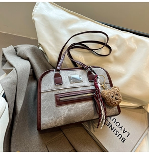 Detail of grey marble texture fabric and reddish-brown leather trim on a shoulder bag