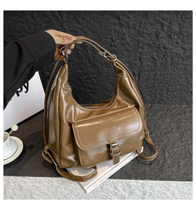 Detail of caramel brown glossy hobo bag featuring white stitching and flap outer pocket