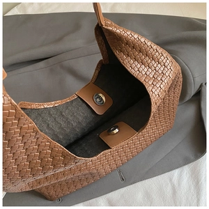 Dettaglio dell'interno della borsa tote intrecciata marrone con chiusure magnetiche