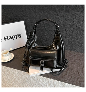 Detail of glossy black hobo bag featuring white contrast stitching and silver hardware
