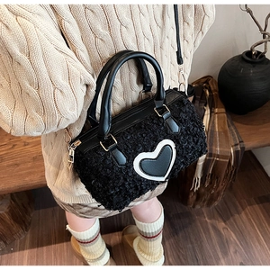 Detail of black faux fur Boston bag with a bold heart patch shown on a model