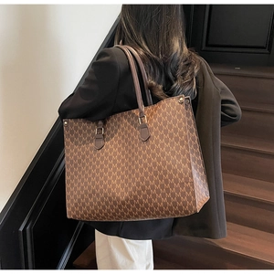 Close-up of vintage brown tote bag with M-pattern print and leather handles on stairs