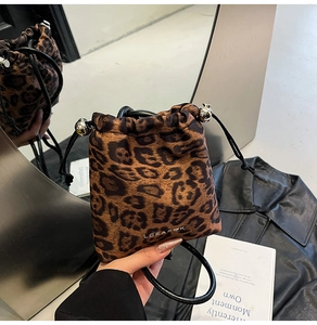 Detail of leopard print drawstring bag with silver hardware and leather handle
