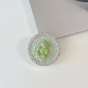 Detail of green bear phone socket grip with sparkling rhinestones and cracked texture