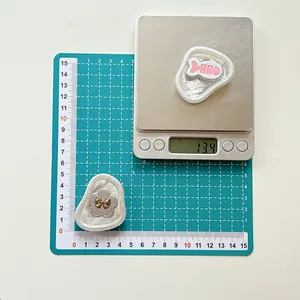 Macro detail of cartoon flower and fishbone phone grips showing precise 13.4g weight on scale