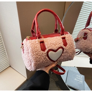 Detail view of pink fluffy pillow bag with red leather circular handles and heart patch