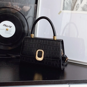 Classic black crocodile pattern handbag with gold clasp on retro vinyl record background