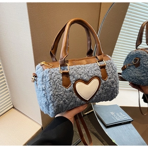 Close-up of sky blue faux fur cylinder bag with brown leather handles and heart patch