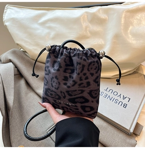 Detail of leopard print drawstring bag featuring metallic beads and white logo accent