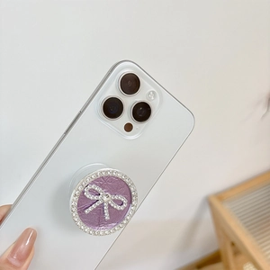 Detail der runden Handyhalterung mit lila Leder und Strass-Schleife auf weißem Smartphone