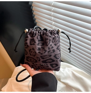 Close-up of leopard print bucket bag featuring drawstring closure and metal ball detail