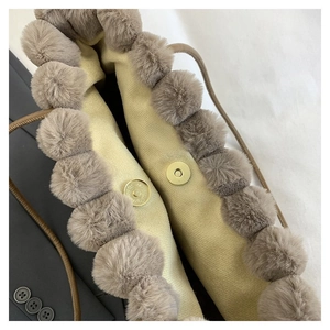 Détail du sac cabas en peluche montrant le fermoir magnétique et les pompons décoratifs