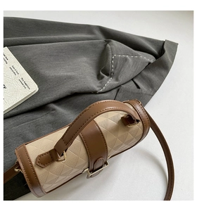 Detail of cylindrical crossbody bag with geometric texture and silk scarf handle accent