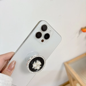 Detail der Handyhalterung mit Perlen und Strasssteinen auf weißem Smartphone