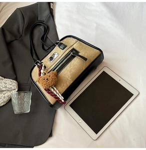 Detail of khaki canvas shoulder bag with leather trim and brown teddy bear charm