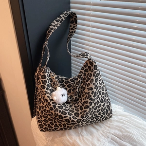 Retro leopard print canvas tote bag with plush charm on elegant white lace fabric background